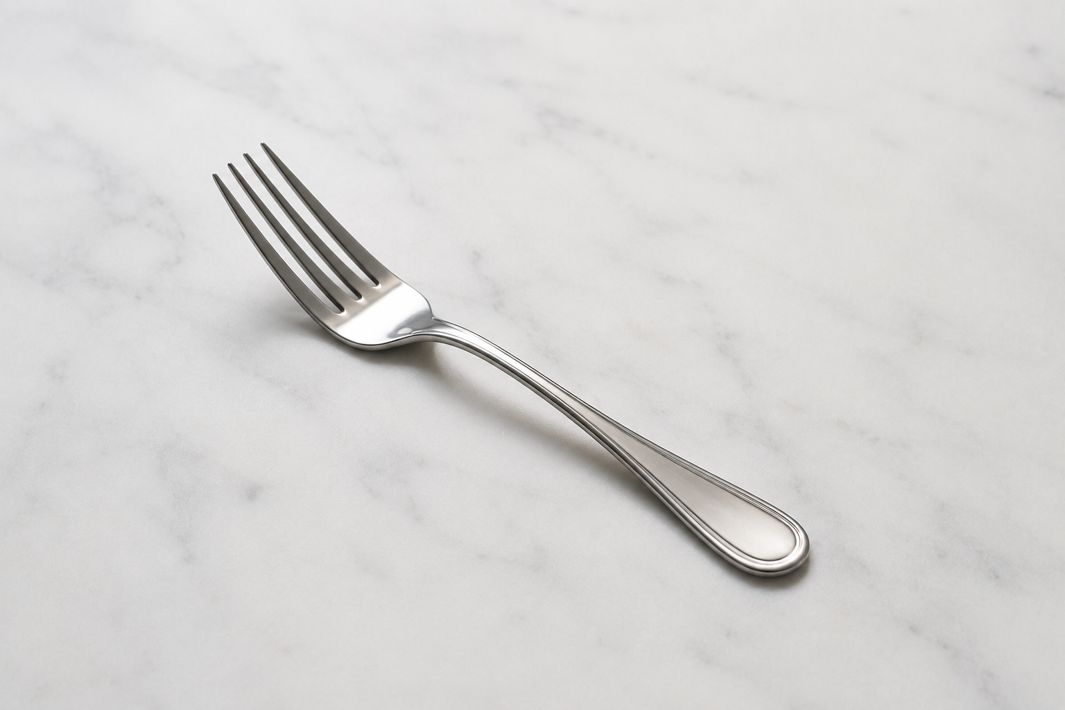 A silver fork resting on a light marble surface.